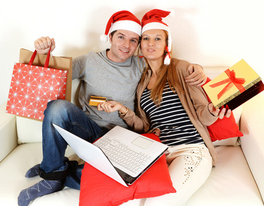 年轻夫妇与便携式计算机在线购物圣诞礼物