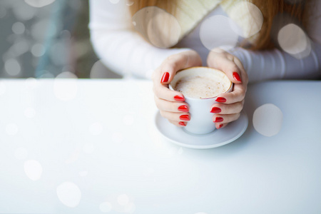 年轻漂亮的女人坐在咖啡厅与一杯咖啡