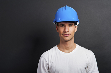 年轻的建筑工人在深色背景上安全帽