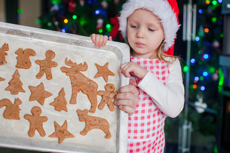 小女孩在圣诞老人的帽子显示她圣诞姜饼曲奇饼