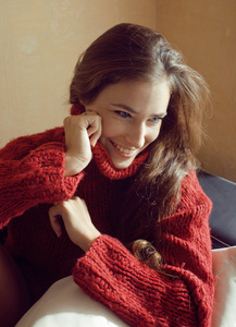 可爱的年轻女子，穿了件毛衣在家里微笑