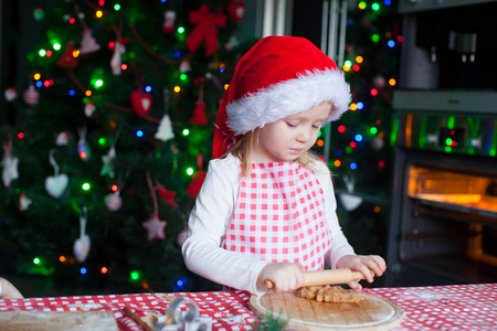 可爱的小女孩，在圣诞老人的帽子烘烤圣诞姜饼曲奇饼