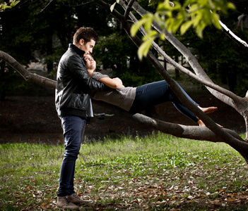 英俊的男人拥抱的女孩躺在树枝上