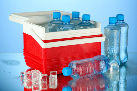旅行冰箱用瓶的水和冰的多维数据集，在蓝色背景