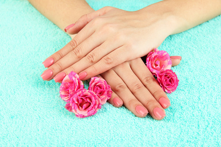 女人手中粉红色修指甲和鲜花的色彩背景