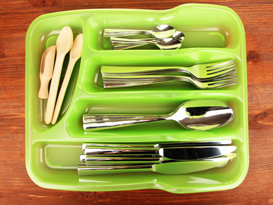 与检查的餐具和木勺子木桌上的绿色塑料餐具托盘