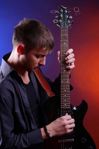 年轻的音乐家，弹吉他，在深色背景上