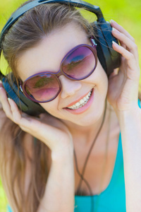 年轻漂亮的女人听听音乐，戴着耳机在户外