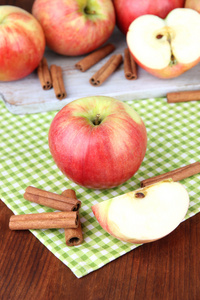 成熟的苹果与肉桂棍棒彩色木制背景上