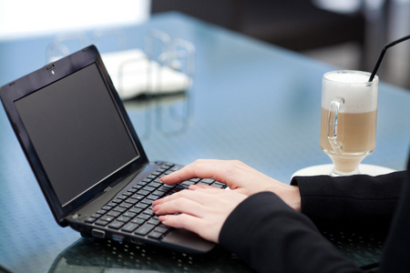 美丽微笑的女人，坐在一个咖啡馆与室外的笔记本电脑的肖像