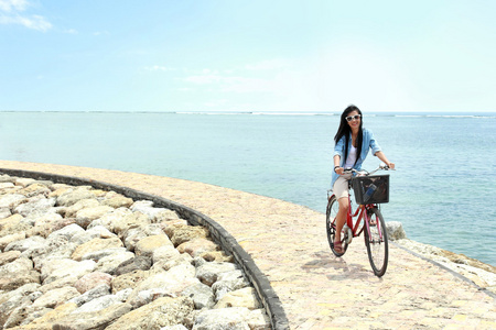 开心的女人骑着自行车在海滩