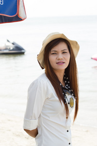 亚洲女人在热带海滩上的漂亮的帽子