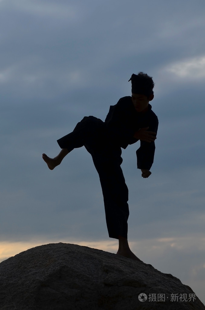 执行pencak silat, 马来传统学科武术的年轻男孩的身影照片-正版商用