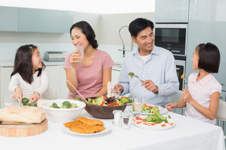年轻的四人家庭享受健康的一餐，在厨房里