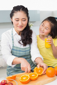 她年幼的女儿切削水果在厨房里的女人