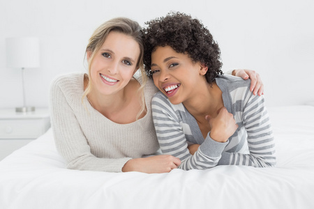 两个年轻的女性朋友，躺在床上微笑