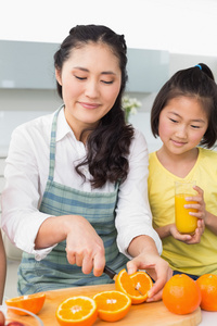 她年幼的女儿切削水果在厨房里的女人