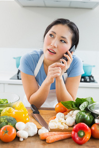 在厨房里用手机在蔬菜的女人