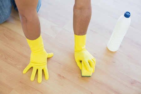 用海绵擦地板的黄色戴着手套的手