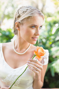 微笑着握橙色玫瑰珍珠项链的金发新娘