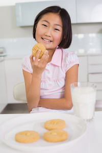 微笑的小女孩享受饼干和牛奶