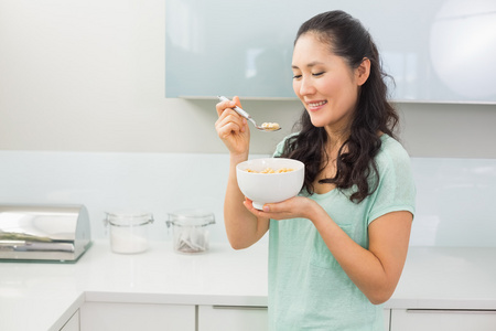 微笑的年轻女人，在厨房里吃谷类食品