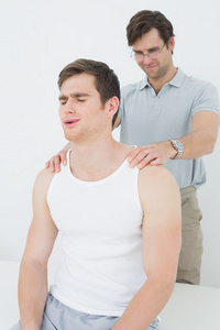 男性理疗按摩一个年轻的男人的肩上