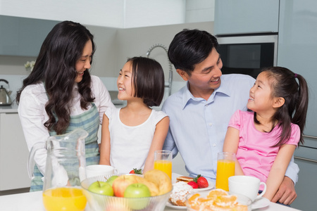 性格开朗的四人家庭在厨房里享受健康的早餐