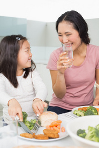 妈妈看着小女孩在厨房里吃的食物