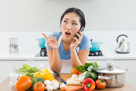 在厨房里用手机在蔬菜的女人