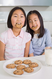 两个女孩享受饼干和牛奶在厨房里