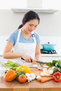 微笑的女人切碎蔬菜在厨房里