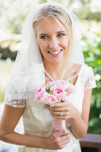 幸福的新娘，抱着她的玫瑰花束的面纱图片