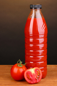 棕色背景上的木桌上瓶中的番茄汁