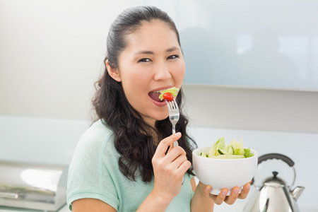 一个女人在厨房里吃沙拉的侧视图肖像