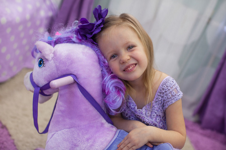 可爱的小快乐女孩和一只玩具马在家里玩