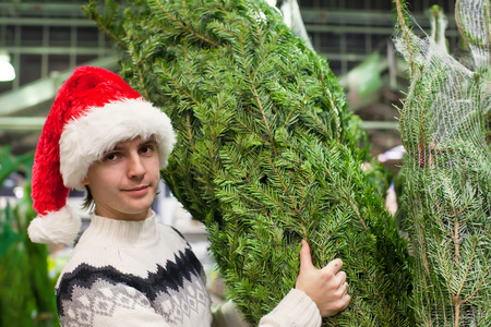 年轻人买店里的一棵圣诞树