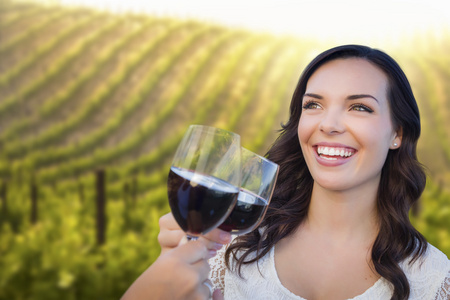 年轻女人享受杯酒中与朋友的葡萄园