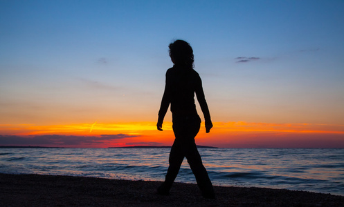 在日落时在沙滩上散步的女人