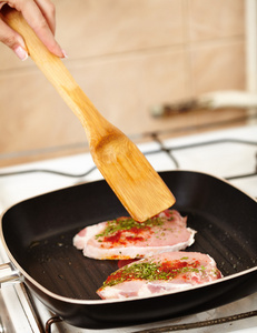 s hand preparing a spiced pork chop in the frying pan