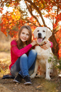 年轻的女孩坐在她的狗猎犬在秋天的场景中与地面上的肖像