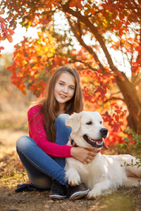 年轻的女孩坐在她的狗猎犬在秋天的场景中与地面上的肖像