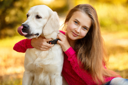 年轻的女孩坐在她的狗猎犬在秋天的场景中与地面上的肖像