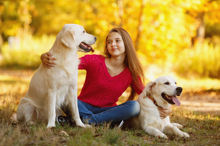 年轻的女孩坐在她的狗猎犬在秋天的场景中与地面上的肖像照片