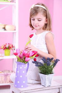 小女孩坐在小梯子上粉红的底色上的花朵