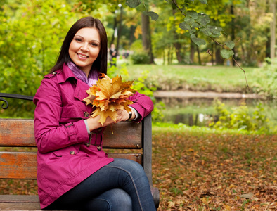 秋天的叶子坐在长凳上的女人