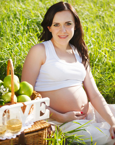 在春天公园里的白色美丽的怀孕女人