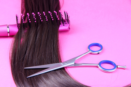 一头棕色的长发，粉红色的背景上的剪刀和梳子