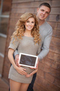 孕妇的丈夫在她肚子上抱着超声波扫描