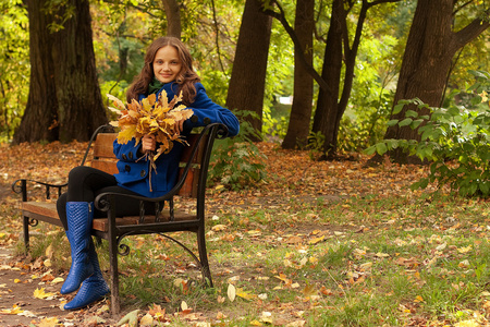 秋天的叶子坐在长凳上的优雅女人